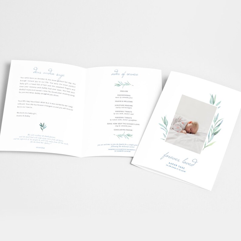 Op de afbeelding: Een wit en blauw begrafenisprogramma met een foto van een slapende baby op een wit deken. Het programma bevat de volgorde van de dienst, een persoonlijk bericht en de woorden "voor altijd geliefd" met de naam en data van de baby.