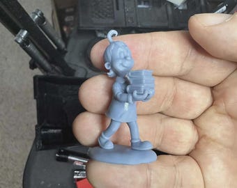 May include: A small, light blue figurine of a cartoon character holding a stack of books. The figure is smiling and wearing a dress and shoes. The figurine is standing on a small, oval base.