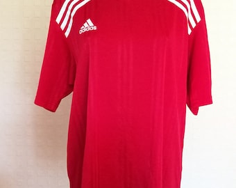 May include: Red short-sleeved t-shirt with white stripes and the Adidas logo on the front.