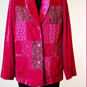 Peut inclure: Un blazer en velours rose avec un motif patchwork composé de différents motifs floraux et géométriques. Le blazer a un col châle et deux boutons de fermeture.