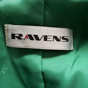 May include: A white label with the word "RAVENS" in black lettering on a green fabric background.