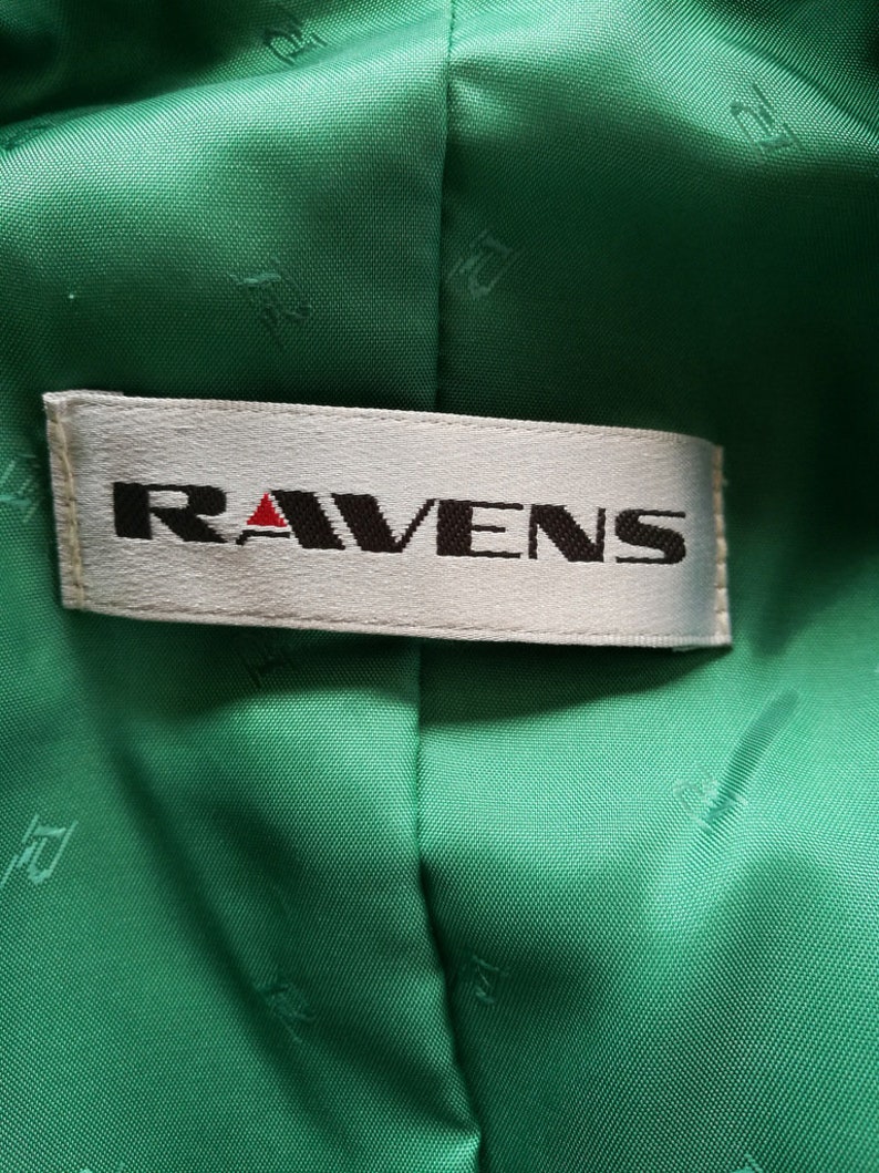 May include: A white label with the word "RAVENS" in black lettering on a green fabric background.