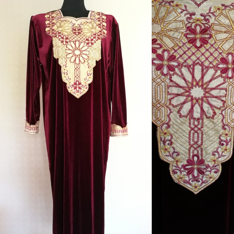 May include: A long, burgundy velvet dress with gold embroidery around the neckline and cuffs. The embroidery features a geometric pattern with floral accents.