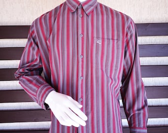 May include: A long-sleeved button-down shirt with vertical stripes in shades of red and gray. The shirt has a small pocket on the left chest with the word "Lee" embroidered in white.
