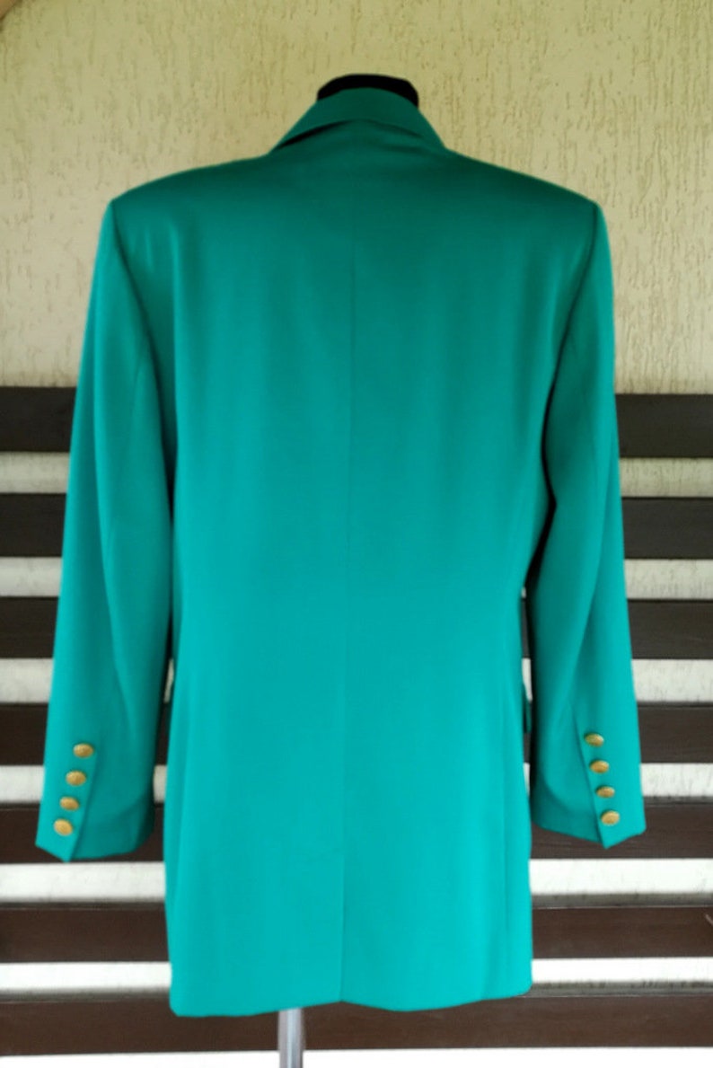 May include: A teal blazer with gold buttons. The blazer is long-sleeved and has a classic style.