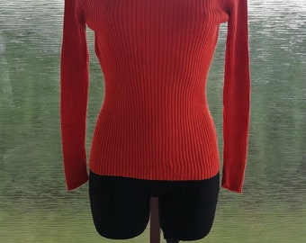 May include: A bright orange ribbed turtleneck sweater on a mannequin.