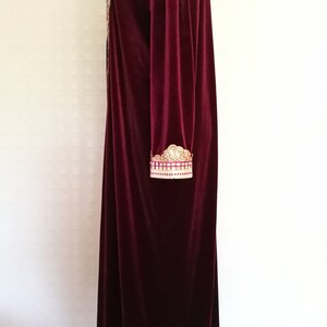 May include: A long, burgundy velvet robe with gold embroidery on the sleeves and neckline.