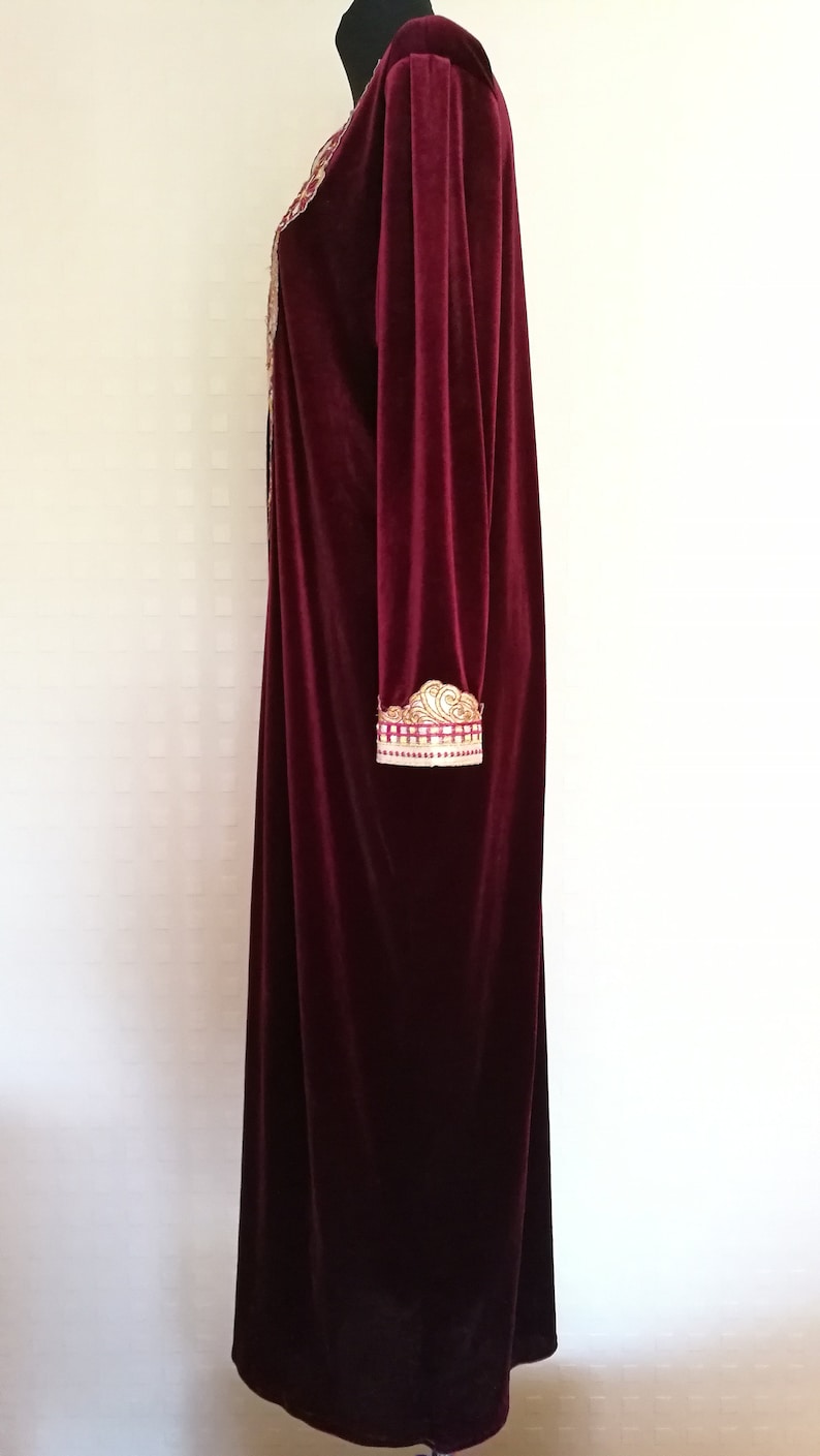 May include: A long, burgundy velvet robe with gold embroidery on the sleeves and neckline.