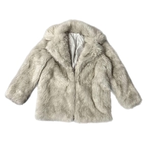 Puede incluir: Un abrigo de piel sintética gris claro con cuello ancho y mangas tres cuartos. El abrigo tiene un aspecto suave y texturizado y un forro de satén. El abrigo está abierto por delante.