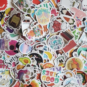 May include: A collection of colorful stickers featuring various designs, including animals, plants, and abstract patterns. The stickers are arranged in a random pattern and include text such as "Kombucha Drinking Hippie" and "Good Vibes".