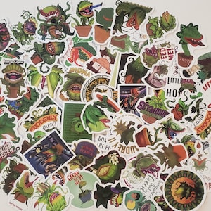 May include: A collection of colorful stickers featuring various illustrations of carnivorous plants. The stickers showcase different designs, including potted plants, open mouths, and text like "Feed Me!" and "Little Shop of Horrors."