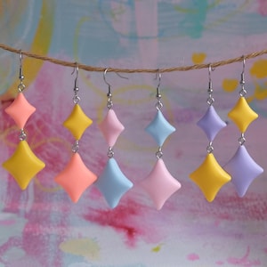 May include: Five pairs of dangle earrings with a geometric diamond shape. The earrings are made of polymer clay and come in five colours: yellow, pink, light blue, lavender, and orange.