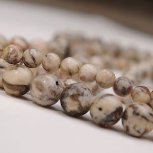 May include: A strand of white and brown agate beads. The beads are round and have a mottled pattern.