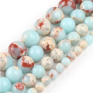 May include: A strand of round, blue and white marbled beads with red accents. The beads are smooth and polished.