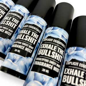 Puede incluir: Varios frascos de bruma perfumada con tapas y etiquetas negras. Las etiquetas dicen "EXHALE THE BULLSHIT" y "Eucalyptus Sweet Mint Fragrance Mist". Los frascos tienen un dise&ntilde;o floral azul y contienen 30 ml de producto.