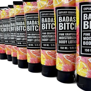 May include: A row of squeeze tubes containing Explicit Essentials Badas Bitch Pink Grapefruit Moisturizing Body Lotion. Each tube features a vibrant pattern of pink grapefruit slices and hibiscus flowers, with a black cap and 150 ml / 5 fl oz label.
