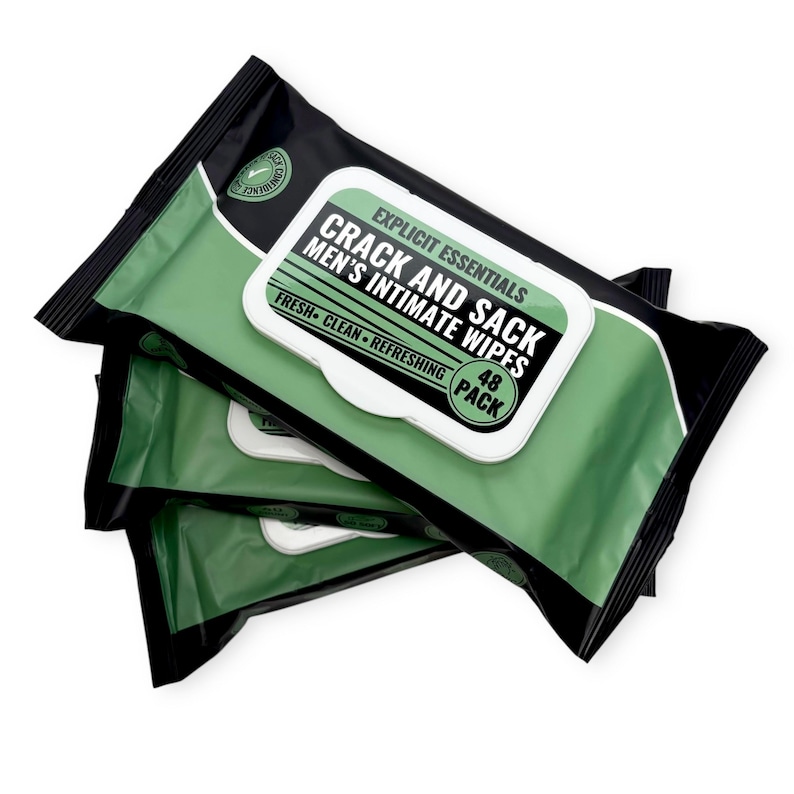 May include: Three packs of "Crack and Sack Men's Intimate Wipes". The packaging is black and green with a white label. The label reads "Explicit Essentials" and "Fresh + Clean + Refreshing". The pack contains 48 wipes.
