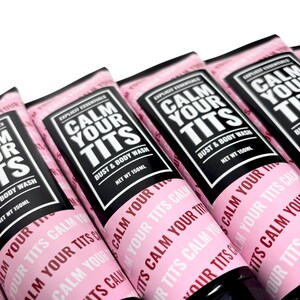 May include: Several pink tubes of "Calm Your Tits" bust and body wash, each with a black label and white text. The tubes are labeled "Explicit Essentials" and contain 150ml of product. The phrase "Calm Your Tits" is repeated on the tube.