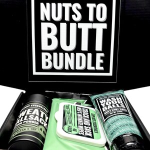May include: A black box set with the text "NUTS TO BUTT BUNDLE" in white. The box contains a black container of "SWEAT ALLSACK" powder, a pack of "CRACK AND SACK" wipes, and a tube of "WASH YOUR BALLS" body wash.