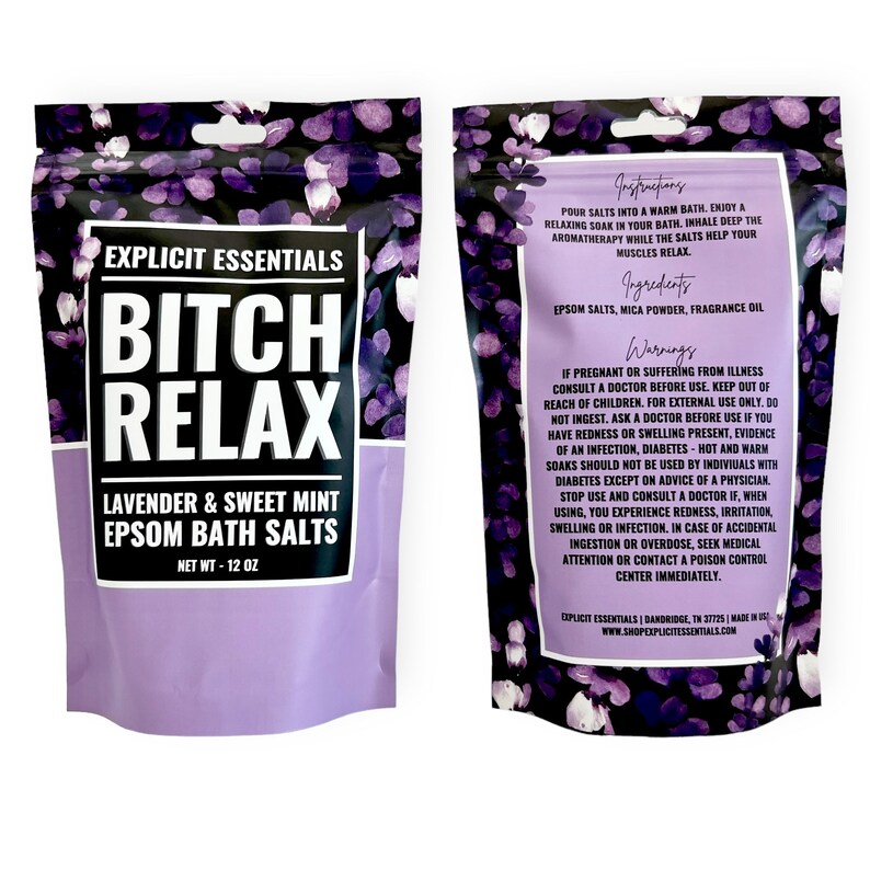 Op de afbeelding: Een staande zak met Explicit Essentials Bitch Relax Epsom-badzout met lavendel en zoete munt. De voorzijde heeft een paars bloemenpatroon en vette tekst. De achterzijde bevat instructies, ingredi&euml;nten en waarschuwingen voor het badzout.