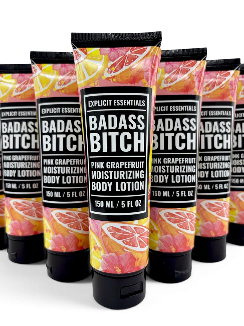 May include: A group of five squeeze tubes of Explicit Essentials Badass Bitch Pink Grapefruit Moisturizing Body Lotion. Each tube features a black cap, a black label with white text, and a background pattern of pink grapefruit slices and flowers.