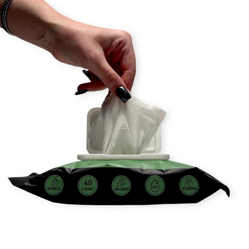 May include: A package of white, soft wipes with a green and black label. The label includes the text "GENTLE", "40 COUNT", "SO SOFT", "PH", and "HYGIENIC". A hand is pulling a wipe from the package.