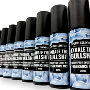 Puede incluir: Una fila de botellas de spray negras con tapas negras. Las etiquetas muestran el texto "EXHALE THE BULLSHIT" en blanco, as&iacute; como "Eucalyptus Sweet Mint Fragrance Mist" y "30 ml". Las etiquetas tienen un dise&ntilde;o azul y blanco.