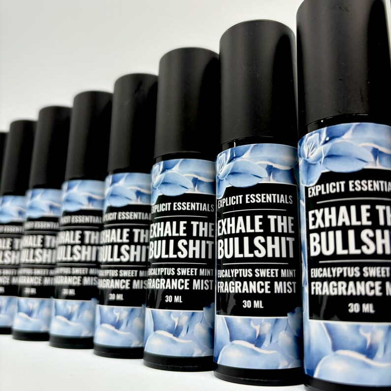 Puede incluir: Varias botellas de bruma perfumada con tapas negras y etiquetas que dicen "EXHALE THE BULLSHIT". Las etiquetas presentan un dise&ntilde;o floral azul y blanco y el texto "Eucalyptus Sweet Mint Fragrance Mist, 30 ml."