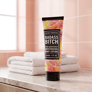 May include: A squeeze tube of Explicit Essentials Badass Bitch pink grapefruit moisturizing body lotion. The packaging features a black label with white text and a colorful citrus and floral print. The tube contains 150 ml / 5 fl oz of lotion.