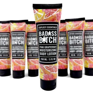 May include: A group of squeeze tubes of Explicit Essentials Badass Bitch pink grapefruit moisturizing body lotion. Each tube features a black cap and a label with a pink grapefruit and floral pattern, containing 150 ml or 5 fl oz of product.