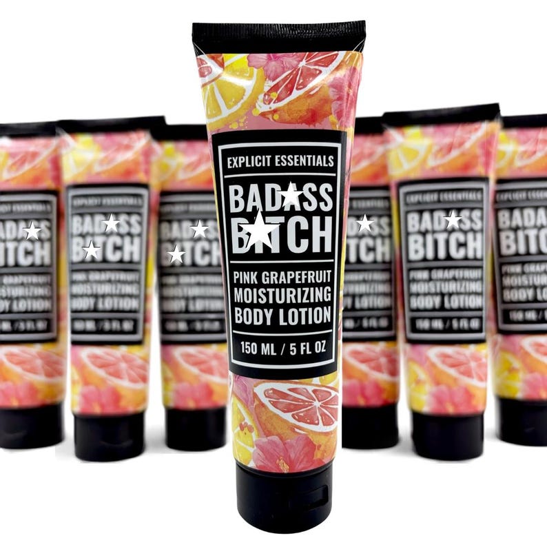 May include: A group of squeeze tubes of Explicit Essentials Badass Bitch pink grapefruit moisturizing body lotion. Each tube features a black cap and a label with a pink grapefruit and floral pattern, containing 150 ml or 5 fl oz of product.