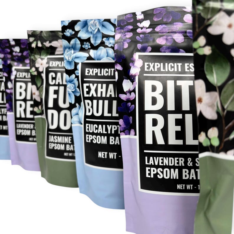 May include: A row of colorful bath salt pouches with floral designs. The pouches feature text like "Calm", "Exhale", and "Bit Rel". Each pouch has a different color scheme, including blue, green, and purple, with a black top.