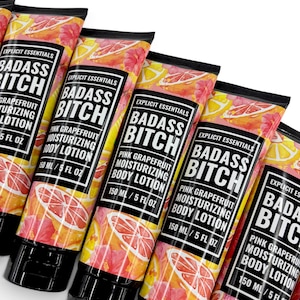 May include: Multiple tubes of Explicit Essentials Badass Bitch pink grapefruit moisturizing body lotion. Each tube features a vibrant pattern of pink grapefruit slices and yellow citrus on a white background, with a black cap and 150 ml / 5 fl oz label.