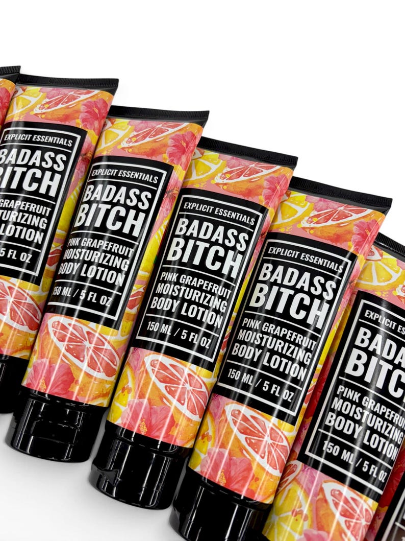 May include: Multiple tubes of Explicit Essentials Badass Bitch pink grapefruit moisturizing body lotion. Each tube features a vibrant pattern of pink grapefruit slices and yellow citrus on a white background, with a black cap and 150 ml / 5 fl oz label.