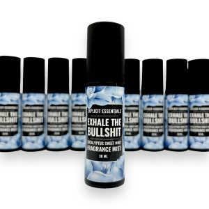 Puede incluir: Una colecci&oacute;n de botellas de bruma perfumada con tapas negras. Las botellas tienen un dise&ntilde;o floral azul y el texto "EXHALE THE BULLSHIT" en letras blancas. El producto est&aacute; etiquetado como "Eucalyptus Sweet Mint Fragrance Mist" y es de 30 ml.