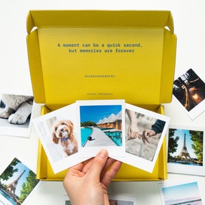 May include: A yellow box with a quote about memories, "A moment can be a quick second, but memories are forever." The box contains a variety of instant photos, including a dog, a tropical beach scene, a couple holding hands, and a view of the Eiffel Tower.