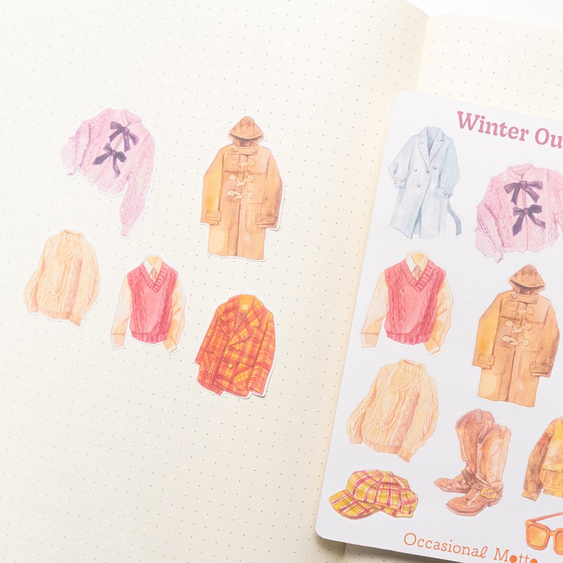 May include: A sheet of stickers featuring illustrations of winter clothing, including sweaters, coats, hats, boots, and scarves. The stickers are in various colors, including brown, beige, pink, blue, and red. The text "Winter Outfit" and "Occasional Motto" are printed on the sheet.
