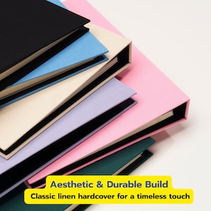 May include: A stack of hardcover books with linen covers in black, light blue, cream, lavender, pink, and dark green. A yellow rectangular label at the bottom displays the text: Aesthetic & Durable Build. Classic linen hardcover for a timeless touch.