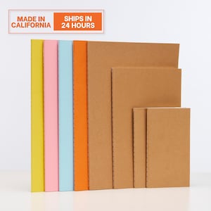 May include: A stack of notebooks in various sizes and colors. The notebooks have colorful spines in yellow, pink, light blue, and orange. The pages are a natural brown color. The text "MADE IN CALIFORNIA" and "SHIPS IN 24 HOURS" is visible.