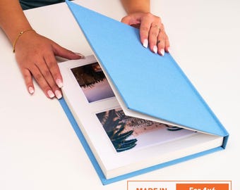 May include: A light blue photo album with white matting, holding 4x6 photos. The album is open, revealing two photographs. The text "MADE IN CALIFORNIA" and "For 4x6 Photos" is visible on the bottom right.