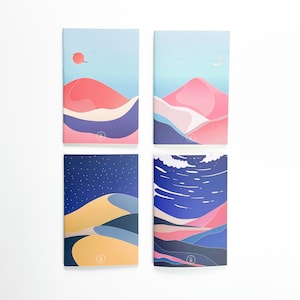 May include: Set of four illustrated notebooks with different landscape designs. Each notebook features a blue sky, a pink mountain range, and a blue and white abstract design. The notebooks are all the same size and have a white background.