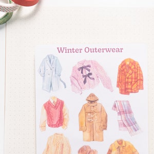May include: A sheet of stickers featuring illustrations of winter outerwear, including a blue coat, a pink sweater with a bow, a plaid jacket, a red sweater vest, a brown peacoat, a plaid scarf, a cream sweater, a brown hat, and a brown leather jacket. The sheet is labeled "Winter Outerwear".