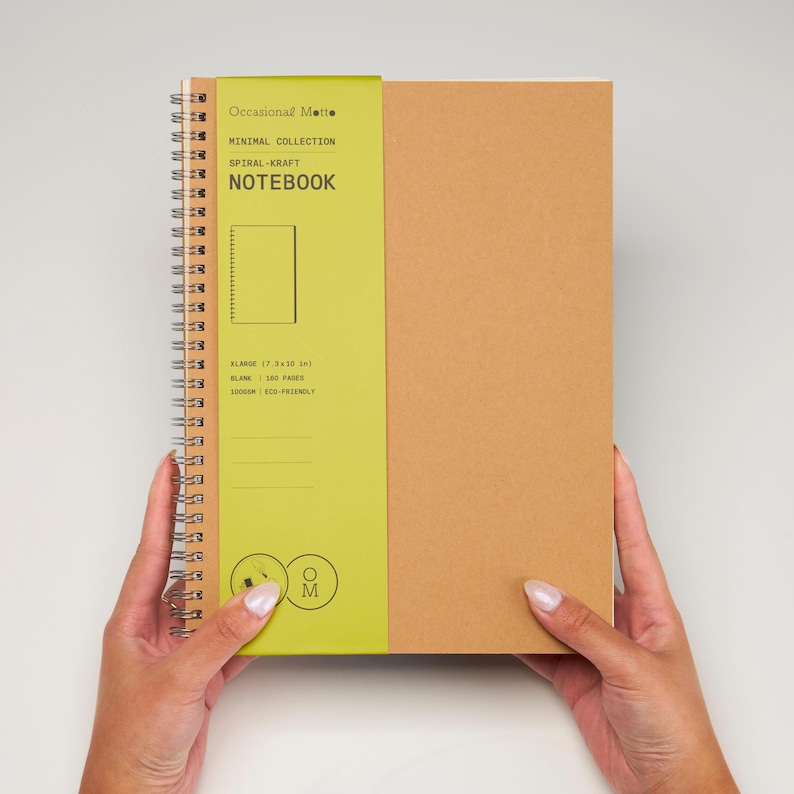 May include: A brown spiral notebook with a green spine. The spine has the text "Occasional Matte", "Minimal Collection", "Spiral-Kraft", and "Notebook". The notebook is 7.34 inches wide and has 100 pages.