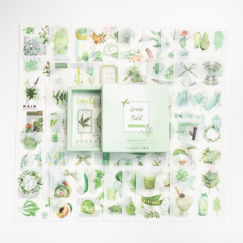 May include: A set of 48 green and white patterned stickers in a clear plastic box. The stickers feature various designs including plants, flowers, and geometric shapes. The box has a green lid with the words "Green Field" and "Occasional Memo" printed on it.