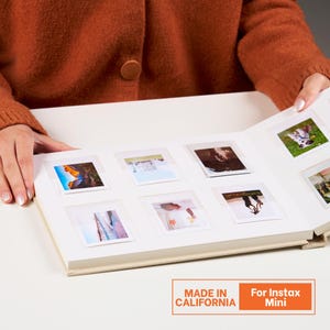 Peut inclure: Un album photo blanc avec plusieurs emplacements carrés contenant diverses petites photographies en couleur. Les pages de l'album sont ouvertes, montrant des images de paysages, de personnes et un chien. Le texte MADE IN CALIFORNIA For Instax Mini est visible.
