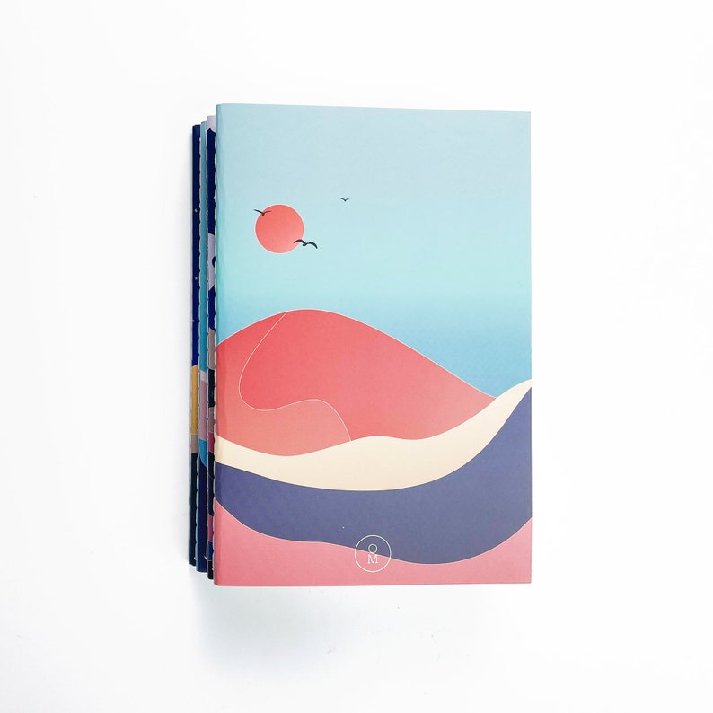 May include: A stack of notebooks with a blue, pink, and white abstract design. The front cover features a red sun, two black birds, and a blue and white wave pattern. The notebook has a small circle with the letters "&M" in the center.
