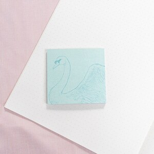 May include: A light blue sticky note with a line drawing of a swan on it. The swan is facing to the right and has its head tilted back.