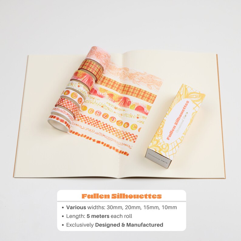 May include: A set of 10 washi tapes with various autumn-themed designs in shades of orange, yellow, and white. The tapes are arranged in a fan shape on a white surface. The text "Fallen Silhouettes" is printed on the box. The tapes are 5 metres long and come in various widths: 30mm, 20mm, 15mm, and 10mm.