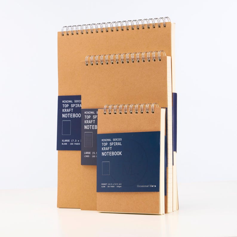 Op de afbeelding: Drie kraftpapier notitieboekjes met wire-o binding. De notitieboekjes zijn op elkaar gestapeld. Het bovenste notitieboekje is het grootste en heeft een blauw label met de tekst "Minimal Series Top Spiral Kraft Notebook". Het middelste notitieboekje is kleiner en heeft een blauw label met de tekst "Minimal Series Top Spiral Kraft Notebook". Het onderste notitieboekje is het kleinste en heeft een blauw label met de tekst "Minimal Series Top Spiral Kraft Notebook".
