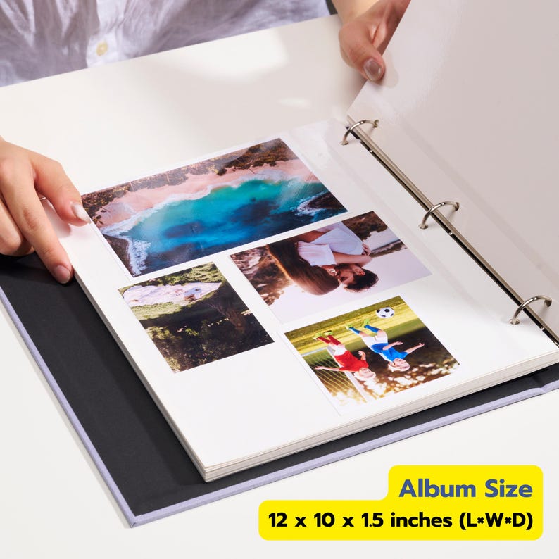 May include: A white three-ring binder photo album with a black interior lining, containing four color photographs on a white page. The album measures 12 x 10 x 1.5 inches. The photos depict a beach, a couple, a forest, and children playing soccer.